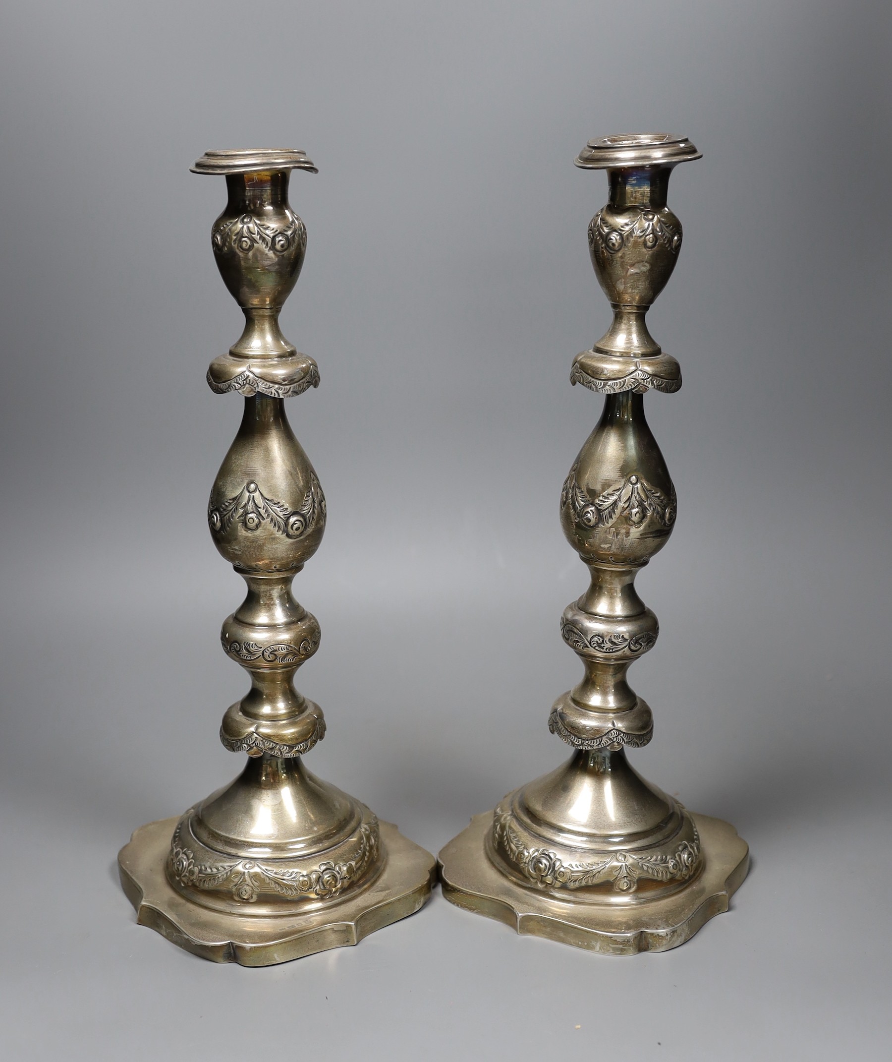 A pair of George V silver candlesticks, with floral swagged knopped stems, London 1924, 36cm, 30.5 oz.